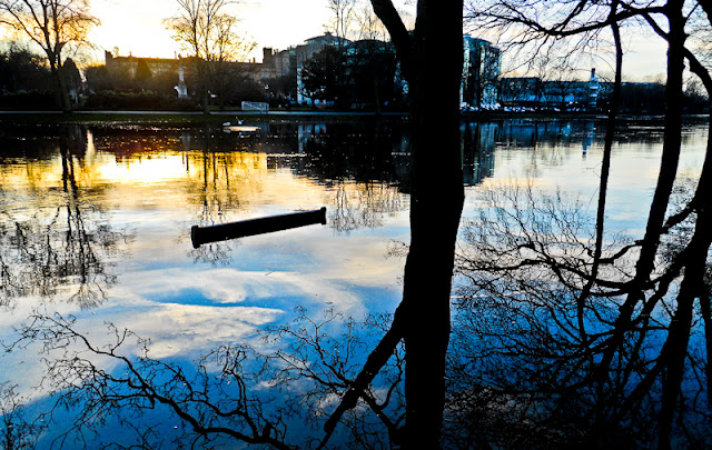 An Evening in York, UK : Posted by Vibha Malhotra on www.travellingcamera.com : When we went to York in winters this year, the last thing we expected to see was a flooded River Ouse. Yet that was the first thing we saw. The long bar in the middle of water in the first photo is actually the top of a wooden bench placed on the side of the river. It would have been interesting to sit on it at this time.The weather was cold and days were short so we decided to start early. We were hoping to see everything in the city by 6 PM because we had a train to catch shortly after that. But we were wrong. We were free by 3:00 PM owing to two things mostly - York being a very small city and our reluctance to chip out money to see anything really.We chanced upon the Yorkshire Museum Gardens where we found the ruins of St. Mary's Abbey at around 3:30 PM and that was to consume the rest of the time of our trip. The Gardens are situated on the banks of the river Ouse and has a cemetary and chapel and also houses the City Art Galery at one end.The ruins in this Garden date back to the 13th century when an extensive rebuilding programme was undertaken and completed. Not much is left of it though. During the day, the lush garden around the ruins make is look very attractive and alive in spite of the age of the buildings.Ruins of the St. Mary's Abbey Church. Walking ahead are my friends Hannah and Kelsey. I love ruins and ancient historical places. There is a mystery around these which only years and years of history can create.Looking at the ruins now, it is very difficult to believe that St. Mary's was once the largest and richest Benedictine establishment in the north of England and St. Mary's Abbey was the largest landholder. A very shocking reminder indeed of the fact that nothing lasts forever.The ruinned Abbey Church and the leafless trees with the setting sun in the backdrop make this place look even more sinister than it actually is. When you are with your friends, the place is charming, but if you are alone...This once used o the Apse of the Norman Church. During the times of its glory, there would have been an altar here. but all that lies here now are some excavated ruins.Days as I mentioned were short and it was late evening by 4:00 PM, so we said good bye to this intriguing piece of history and moved on to the City Art Gallery as the place had started giving us the spooks.