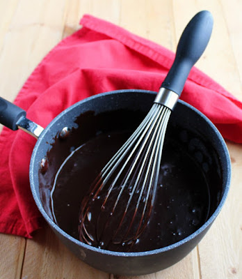 saucepan full of ganache style frosting and whisk