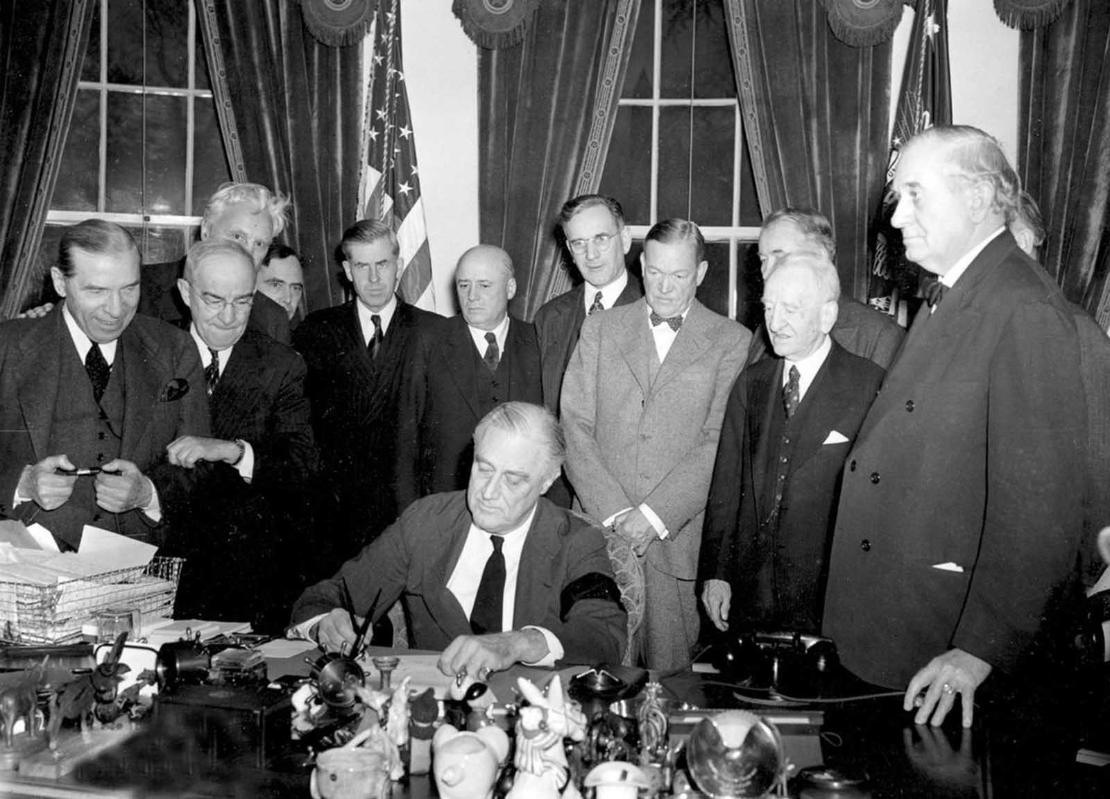 President Roosevelt signs the declaration of war following the Japanese bombing of Pearl Harbor, at the White House in Washington, District of Columbia, on December 8, 1941.