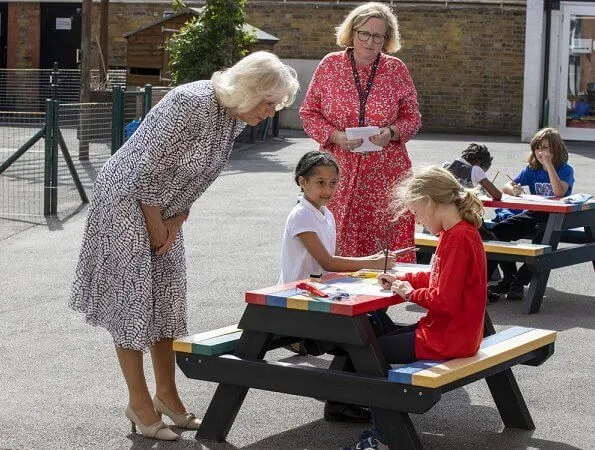 The Duchess of Cornwall is patron of The National Literacy Trust. The duchess wore a printed silk summer midi dress. beige pumps and bag