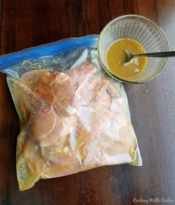 bag of marinating pork chops with a little extra marinade in a bowl nearby