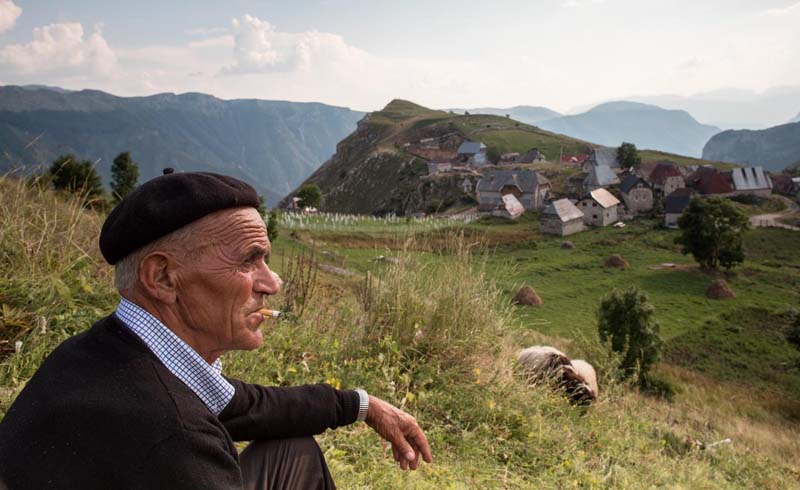 A man takes a cigarette break with a view outside Lukomir.