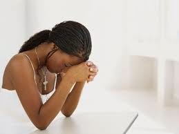 Black girl, cross around her neck, prays