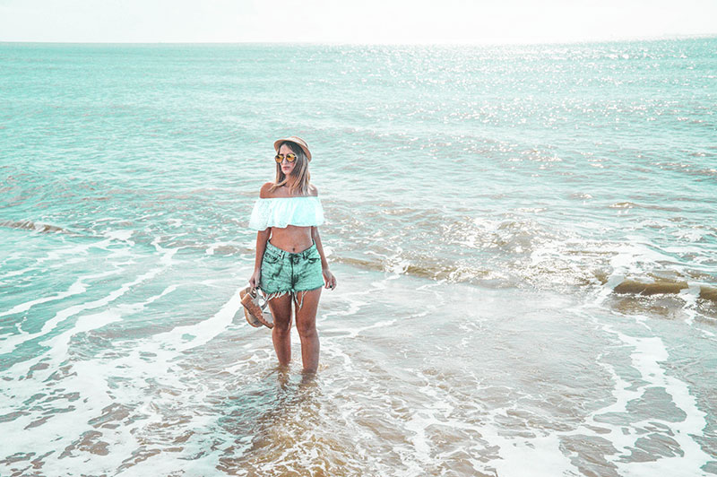 blonde australian blogger stood in tropical sea in crop top and denim shorts blonde australian blogger stood in tropical sea in crop top and denim shorts