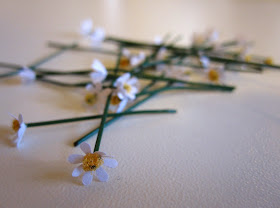 Twenty scattered hand-made miniature daisy flowers stems.