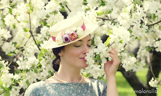 Chica de piel clara y ojos azules con sombrero de flores y almendros en flor en Moscú