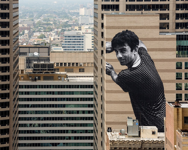 JR recently spent some time in Philadelphia where he was invited by the city's Mural Arts Program to work his craft on the side of a enormous building.