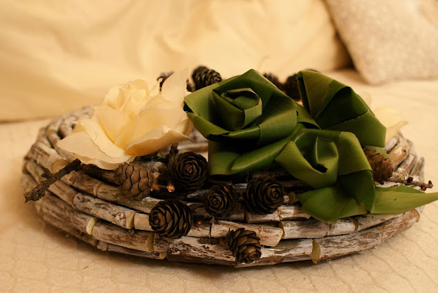 wianek z patyków ozdobiony szyszkami, kremowymi kwiatami i różami z liści