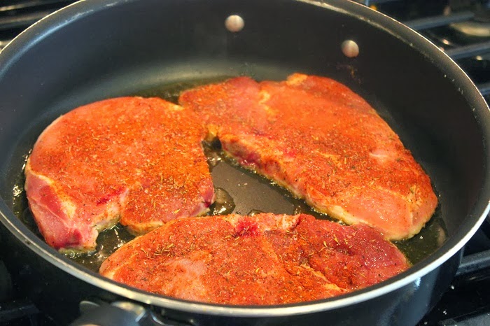 pork chops being seared in pan