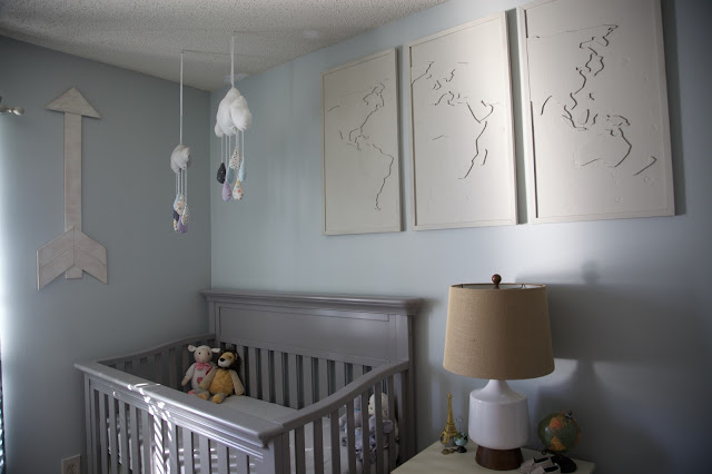 A travel and adventure-inspired gender neutral nursery with pops of pale gray, white, blue, and pale green.