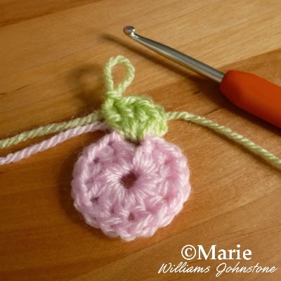 Pink round of crocheted yarn with a second round in pale green started