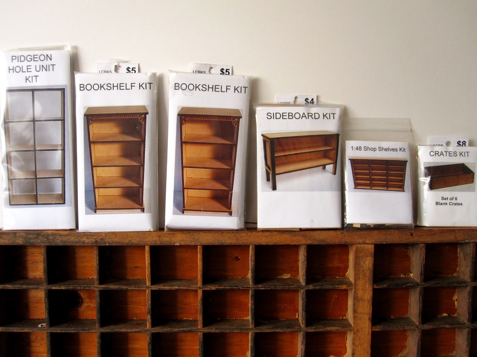 Six miniature wooden furniture kits arranged on top of a printer's tray.