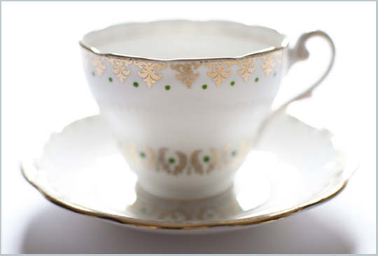 gold and white teacup with green dots