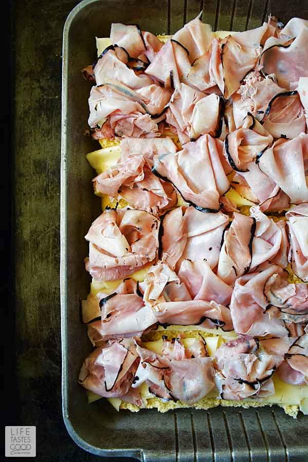 Layering ham on cheese slices to assemble ham and cheese sliders