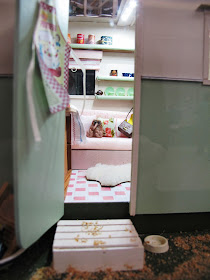 Interior of a one-twelfth scale miniature vintage caravan, with a kiwi stuffed toy on the seat.