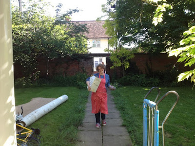 Picture of me in an apron, carrying a box down the front path on moving day when we moved to the country
