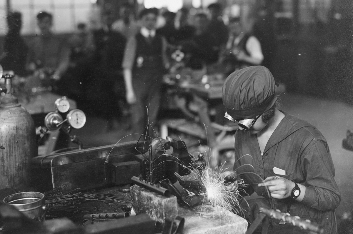 Original caption: Running the welding machine. War time women workers in naval aircraft factory in Philadelphia, Pennsylvania, circa 1918.