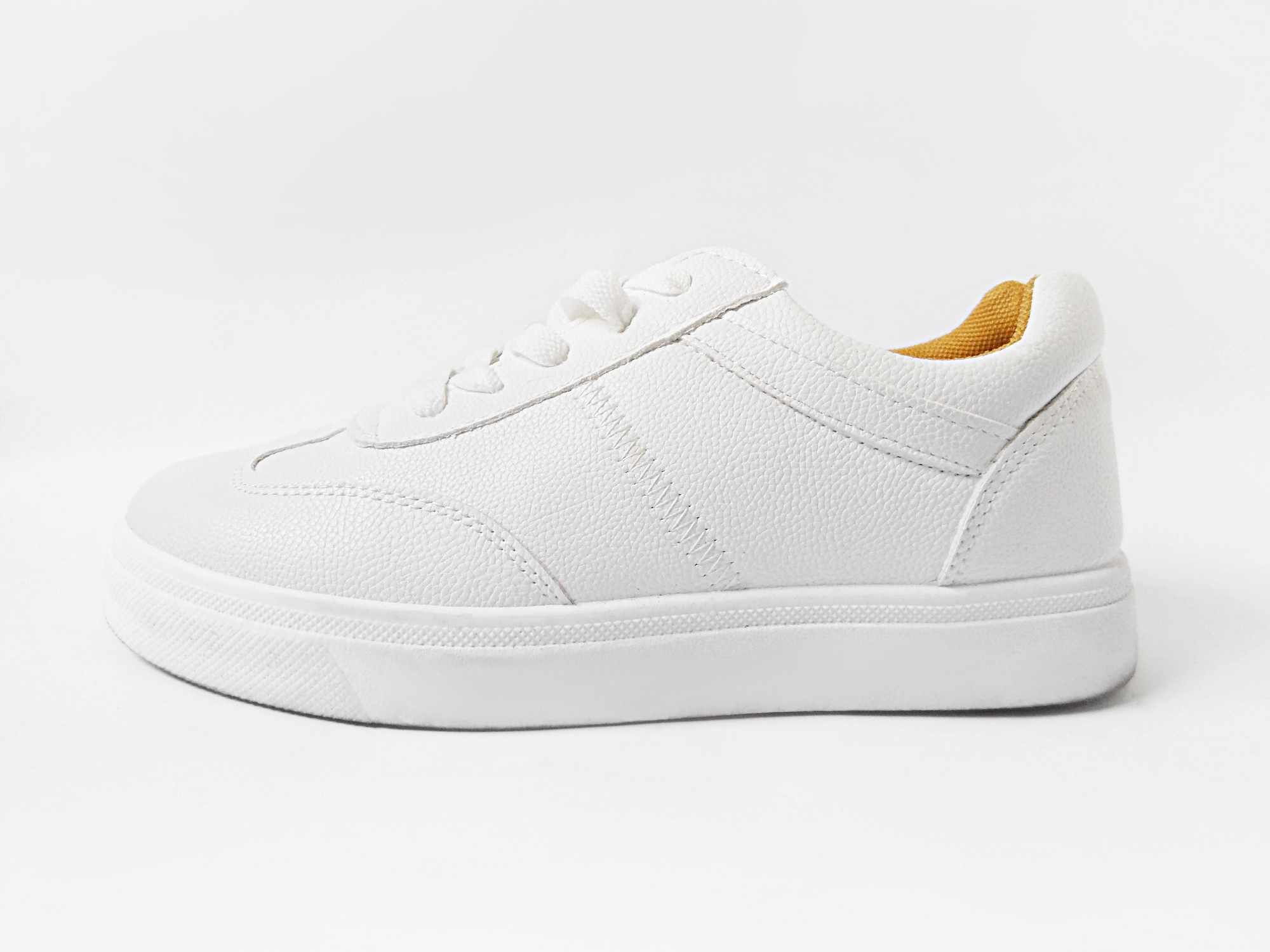 a pair of white basic sneakers in the studio on a plain background