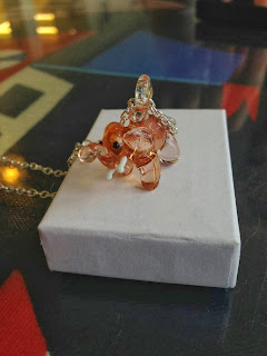 a peach coloured glass elephant pendant on a silver chain