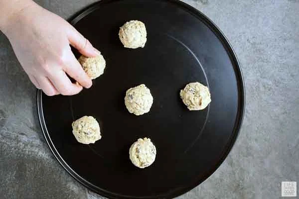 Frozen Quaker Oatmeal Cookie dough balls being placed on a baking tray