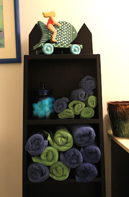 painted blacked shelving unit with towels and sculpture