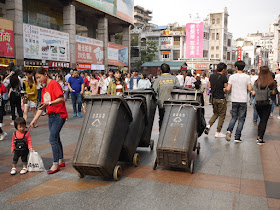 sanitation working pulling five trash bins