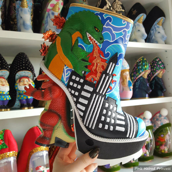 Irregular Choice Family Reunion Jurassotops dinosaur themed ankle boot and heel in hand in front of shoe room shelves