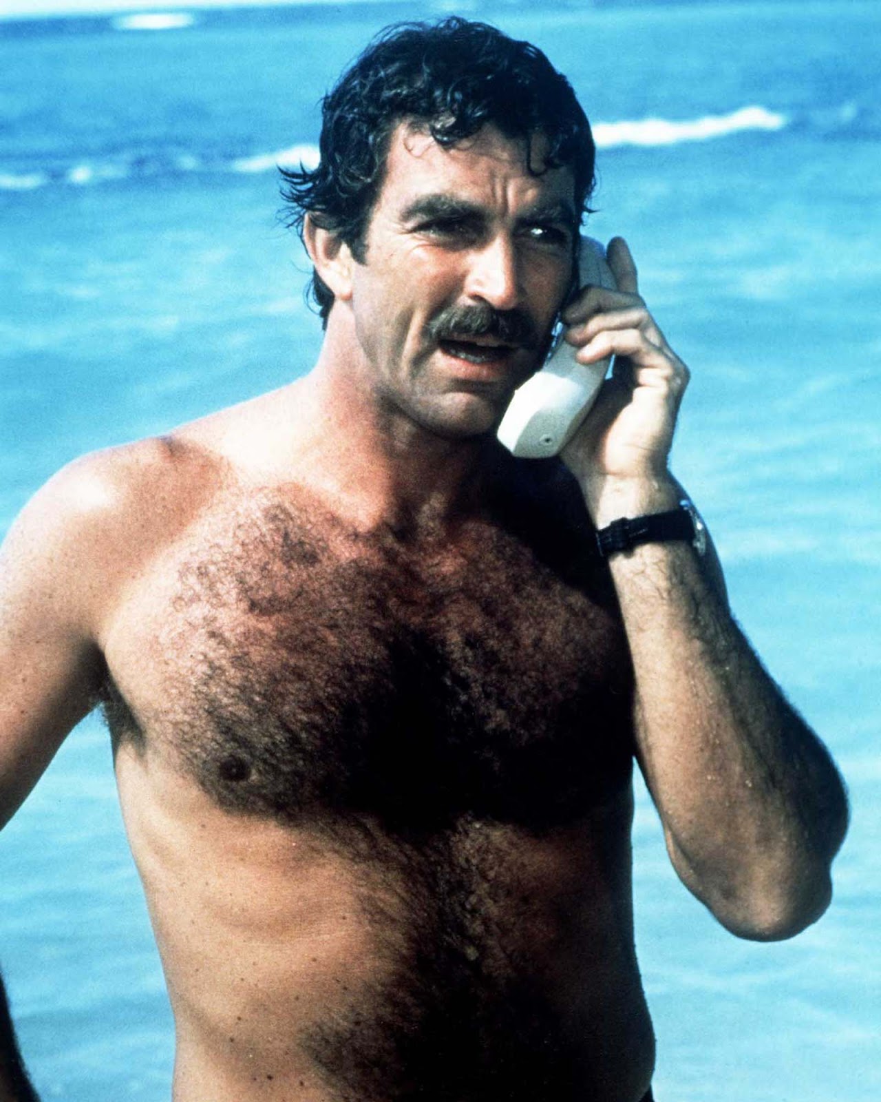 Tom Selleck, a Thomas Magnum magánnyomozó játékában mobiltelefonhívást kezdeményez a tengerpartról a „Magnum PI” sorozatban.  1985.