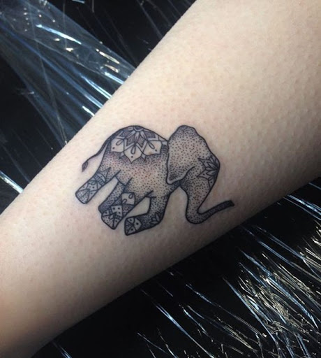 Um rosto de elefante é detalhado com uma série de pontos e elementos comumente visto em mandalas neste tatuagem.