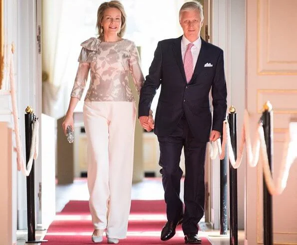 Queen Mathilde Natan blouse from Natan Graphics Couture and carries Diane von Furstenberg silver clutch