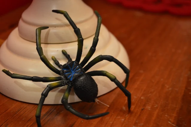 Black Rubber Spider on a white candlestick