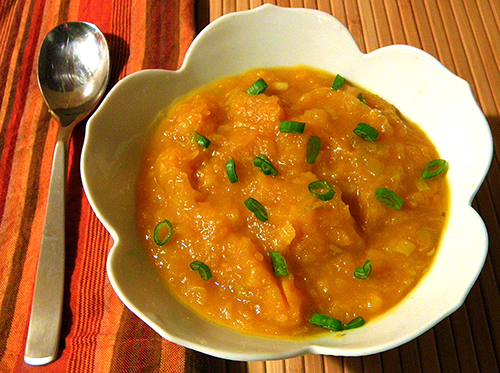 bowl of pumpkin soup topped with green onions