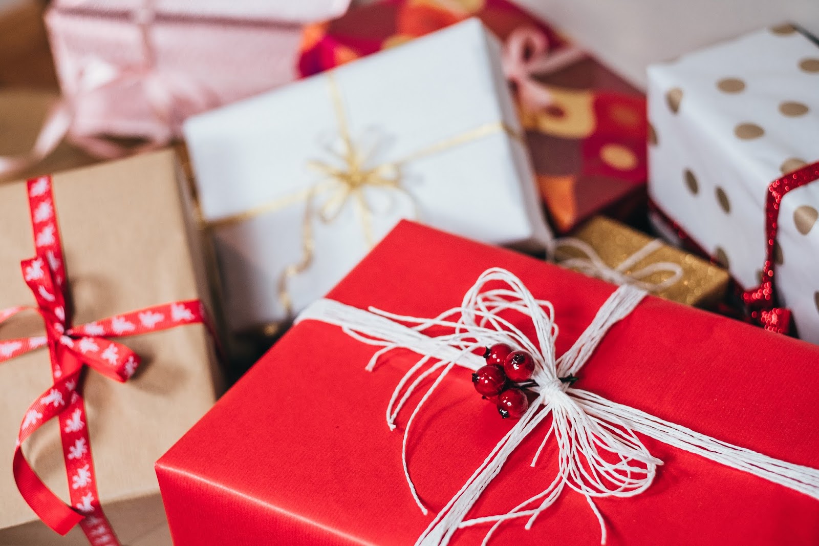 An assortment of Christmas presents wrapped in red, gold and white wrapping paper, some with ribbon in the same colours.