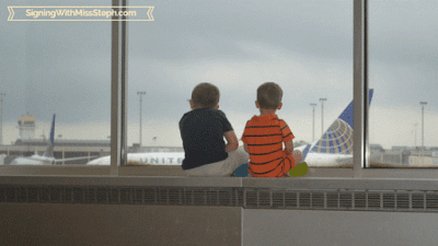 Backs of boys watching planes take off through giant window