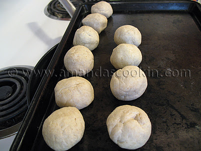 A photo of ten balls of tortilla dough resting on a baking sheet