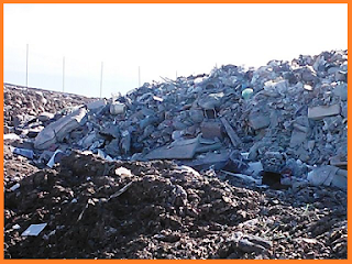 Gray mass of unplowed trash at the landfill surrounded by brown, plowed mass.