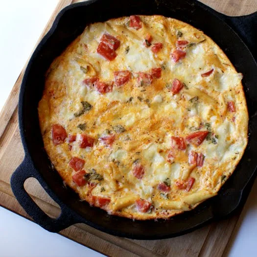 Pasta Frittata in a cast iron skillet on a wood cutting board.