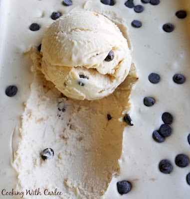 Smooth, creamy and oh so good! This no-churn ice cream is exploding with peanut butter flavor and is dotted with chocolate chips. It is almost too easy! top of frozen ice cream container with first scoop of ice cream