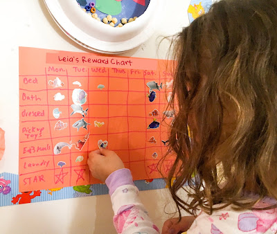 Girl affixes sticker to a chore chart