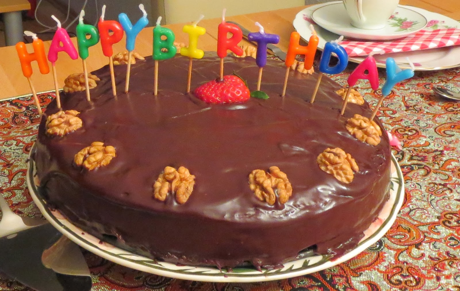 Nusstorte mit Schokoladenüberzug, bunten Geburtstagskerzen und Nuss-Dekoration