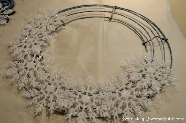 Snowflake ornaments glued halfway around a wire wreath frame