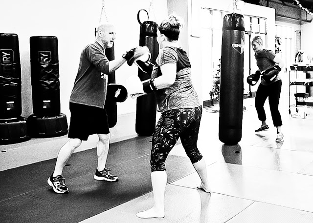 kickboxing students punch bags punch mitts press kettlebells and perform burpees at Fortress Fitness Kickboxing in Morristown TN