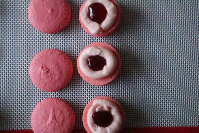 piped macaron buttercream around the edge and a dot of strawberry jam in the middle