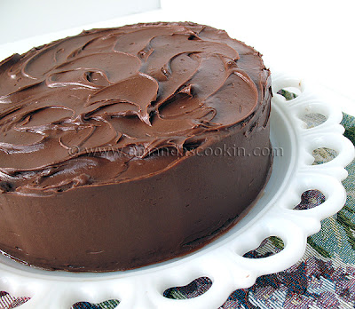 A close up photo of a Nigella\'s old fashioned chocolate cake resting on a white cake stand.