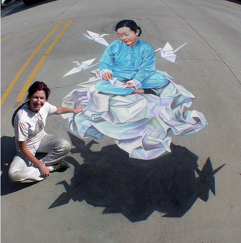 Bağdaş kurup origami kuşları yaparken yerden yükselmiş olan Çinli bir bayan gösteren kaldırım sanatı resmi