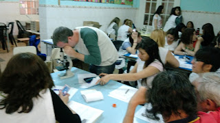 grupo de maestros alrededor de la mesa con un microscopio. Un maestro observa por el ocular