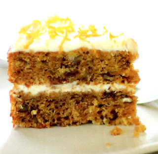 slice from a classic carrot cake with cream cheese filling and frosting and orange zest as a garnish