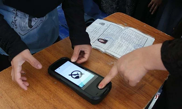 Image Attribute: An Afghan Independent Election Commission (IEC) official (L) scans a voter's finger / Source: Reuters