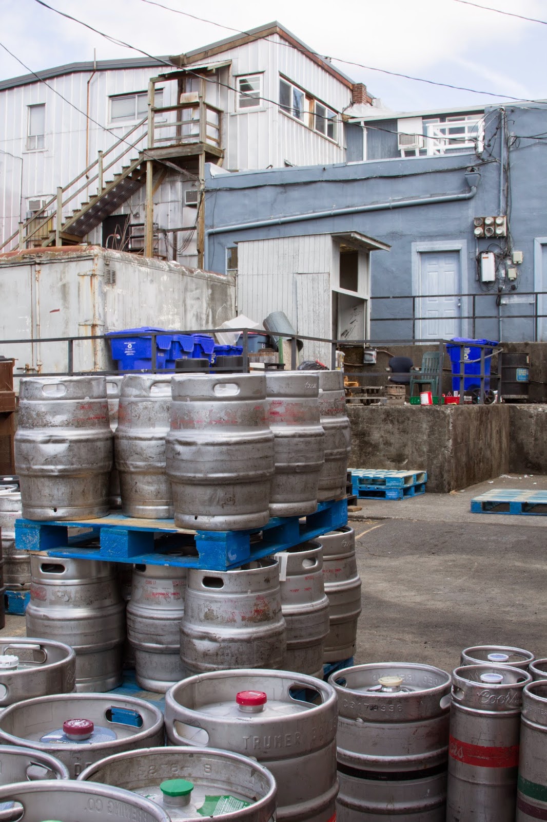 FOLKWAYS NOTEBOOK BEER KEGS IN A PARKING LOT BEHIND MAIN STREET BUILDINGS