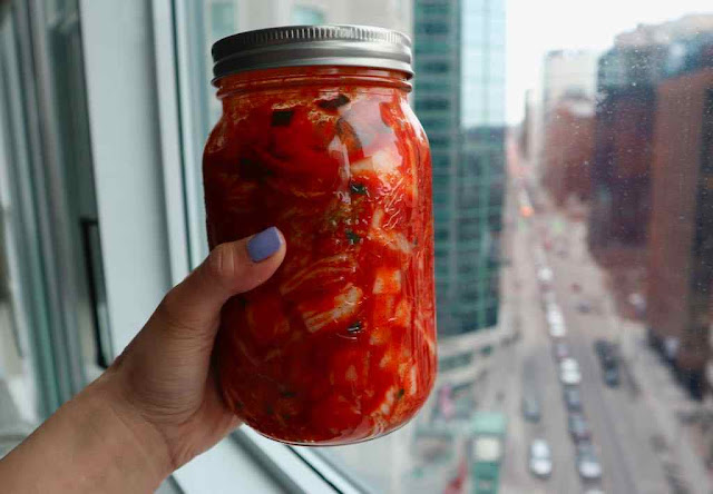 holding a jar of kimchi up